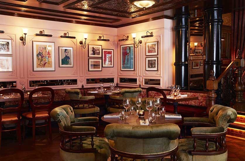 Interiors of The Cadogan Arms pub with green velvet Captain's chairs and antiqued balloon chairs