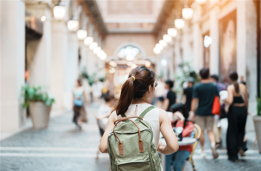 Woman with a backpack works towards people sitting around tables in an arcade 